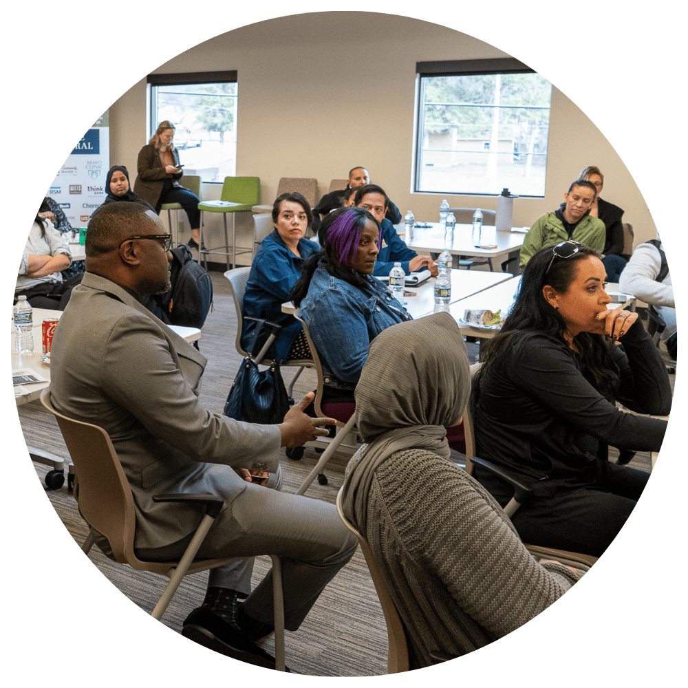 Photo of a room full of diverse people sitting at tables