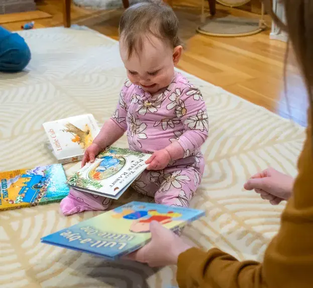 Photo of a smiling baby girl looking at books