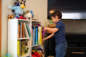 Photo of a young boy pulling a book from a bookshelf